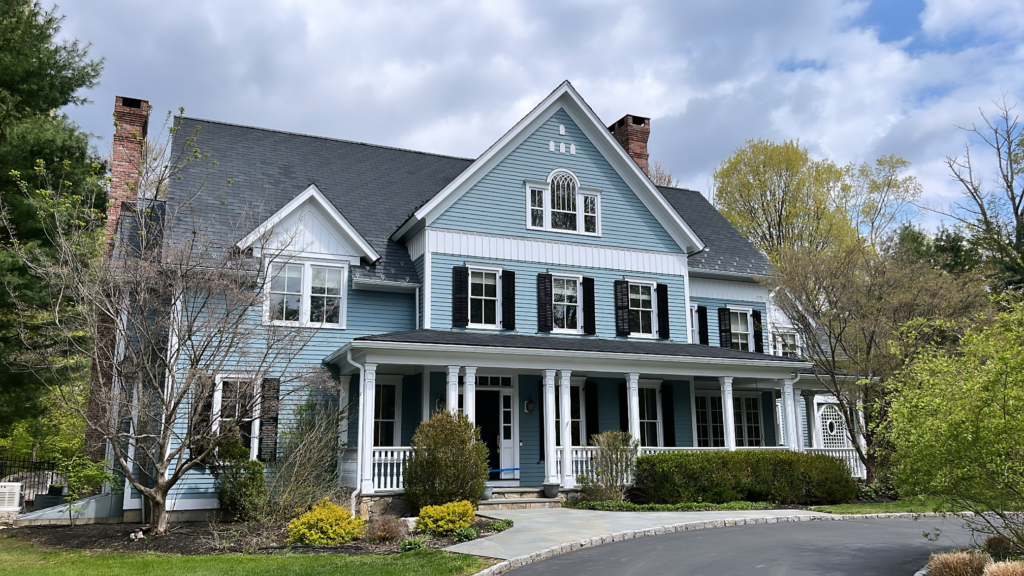 Light blue siding home in Ridgefield, CT with refreshed exterior paint, white trim, black shutters, and a clean front elevation
