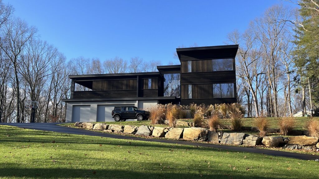 Modern black exterior home in Westport, CT with bold contemporary lines, dark cladding, and a clean hillside front elevation