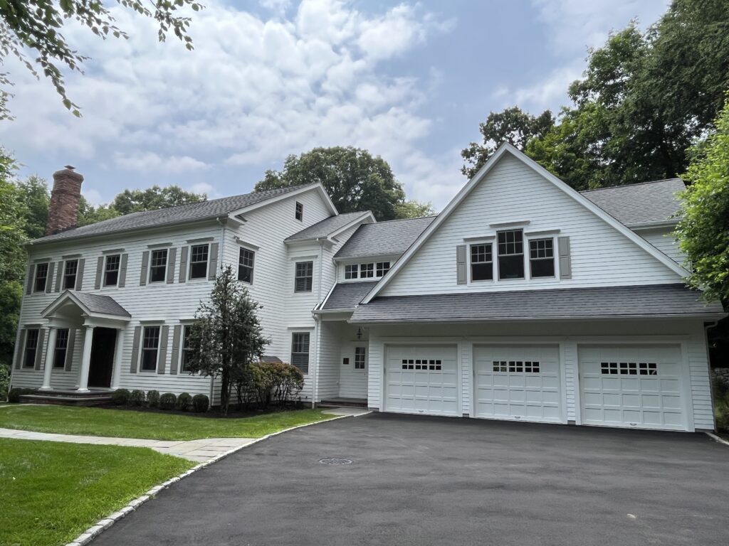 White siding home in Weston, CT with a fresh exterior repaint, clean trim, and a bright front elevation with three-car garage