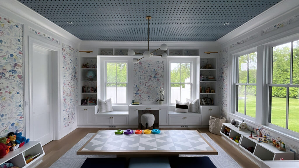 Playroom interior in Westport, CT with white trim, a blue patterned ceiling, and custom built-ins around a bright window wall