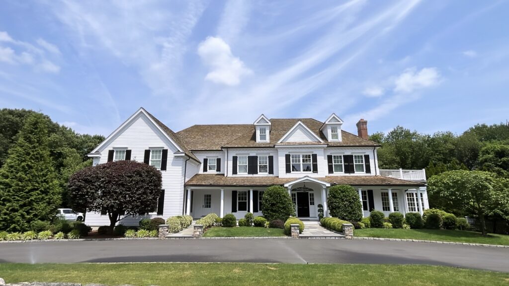 White siding home in New Canaan, CT with black shutters, refreshed exterior paint, and a clean full front elevation