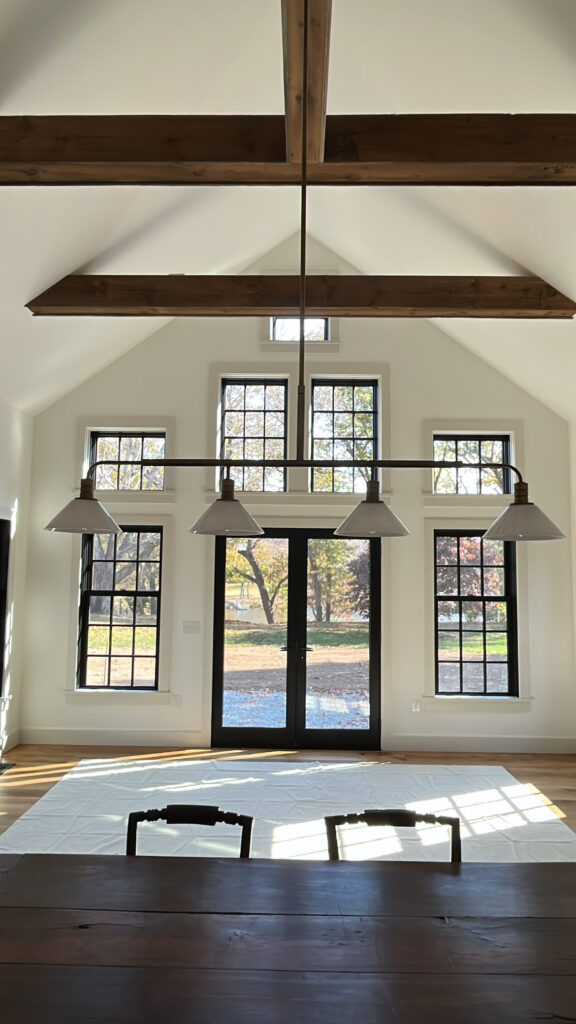 Vaulted interior in Darien, CT with white walls, black window trim, and exposed wood beams in a bright open living space