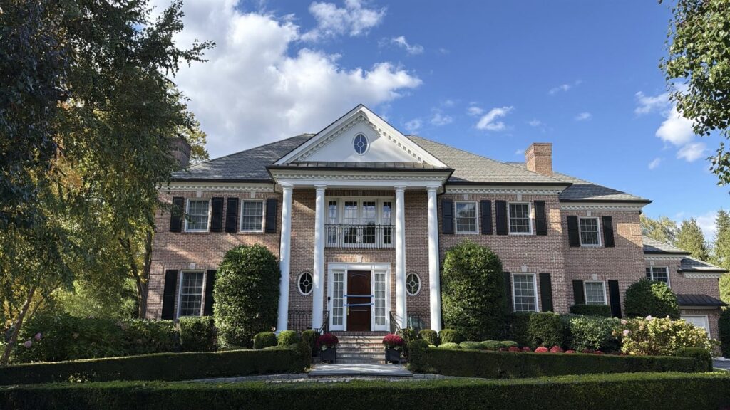 Brick colonial home in Scarsdale, NY with fresh exterior repaint, white trim, and black shutters