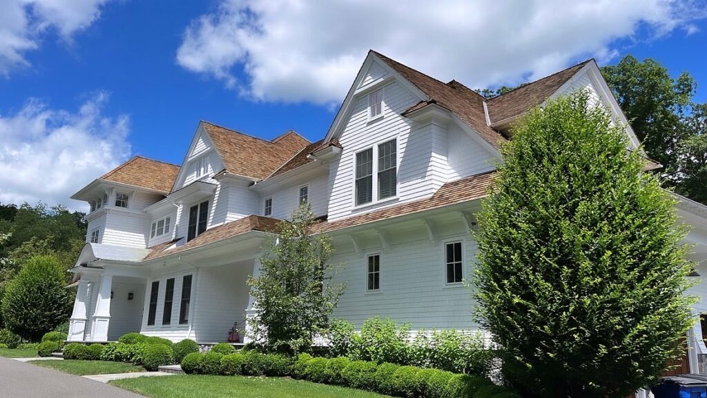 White shingle home in Westport, CT with a fresh exterior repaint, clean trim lines, and a bright side elevation under blue skies