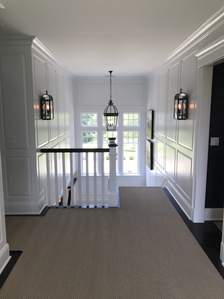 White paneled hallway in Greenwich, CT with crisp trim lines, detailed wall molding, and a clean interior painting finish
