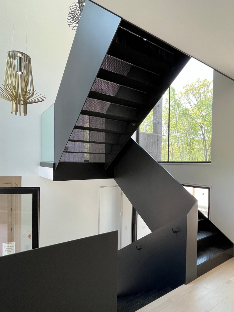 Sculptural black staircase in Westport, CT with a smooth painted finish, sharp modern lines, and dramatic interior contrast