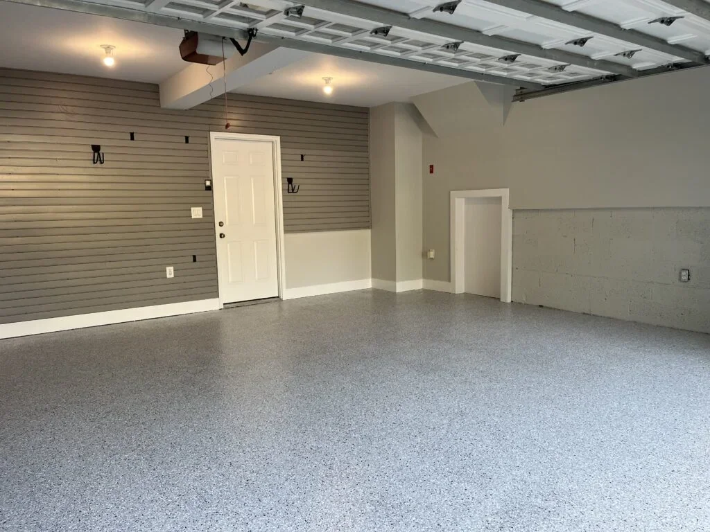 Garage interior in Westport, CT with painted walls, slatwall storage panels, and a gray flake floor coating
