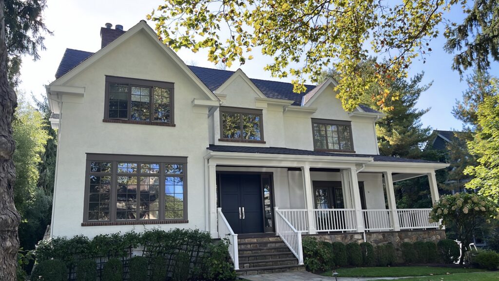 White stucco home in Scarsdale, NY with dark trim accents, black front doors, and a freshly painted front elevation