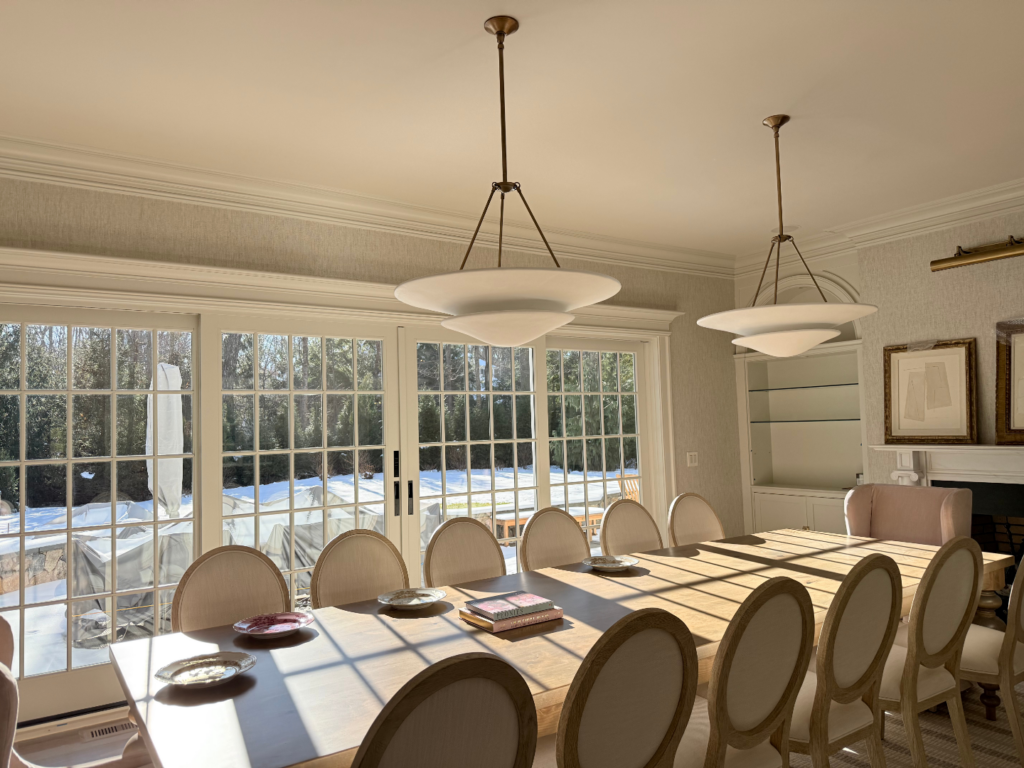 Bright dining room in New Canaan, CT with a clean interior painting finish, large window wall, and warm natural light across the table