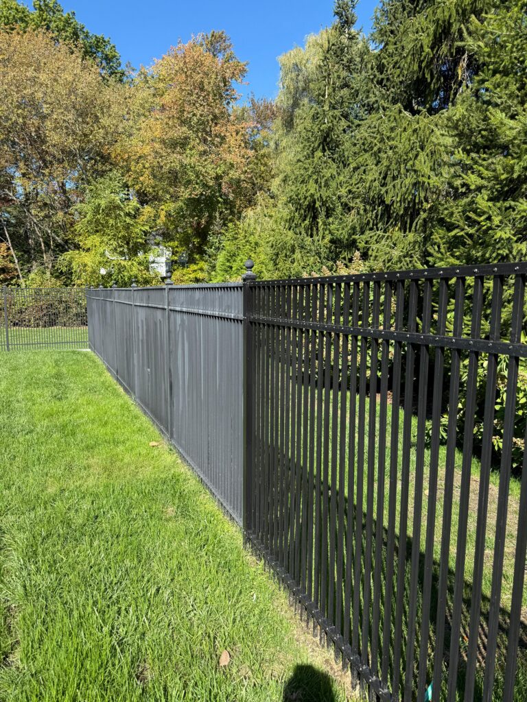 Black metal fence in Scarsdale, NY with a refreshed finish, clean lines, and a polished perimeter appearance along the lawn