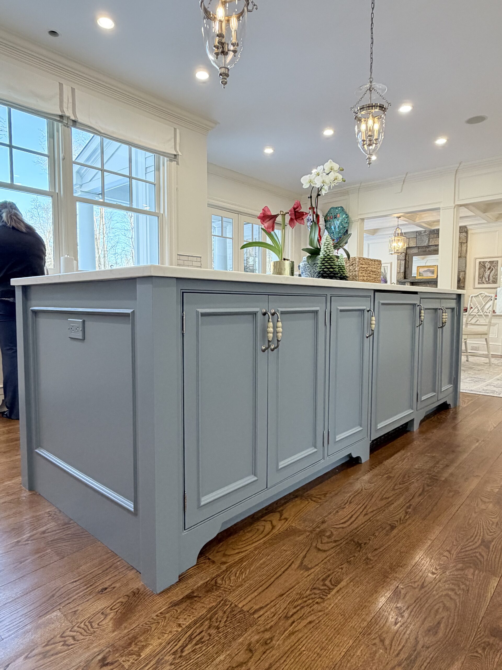 Blue-gray kitchen island in New Canaan, CT with painted shaker panels, decorative hardware, and warm wood flooring