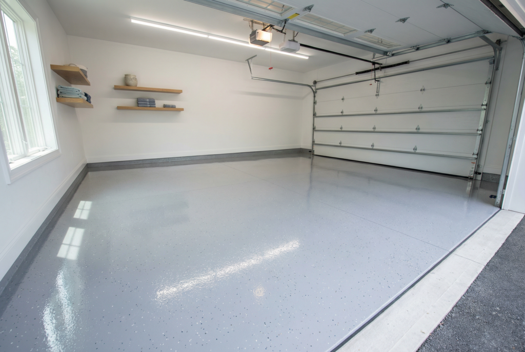 Finished epoxy garage floor with clean gray coating, light reflection, and organized utility space